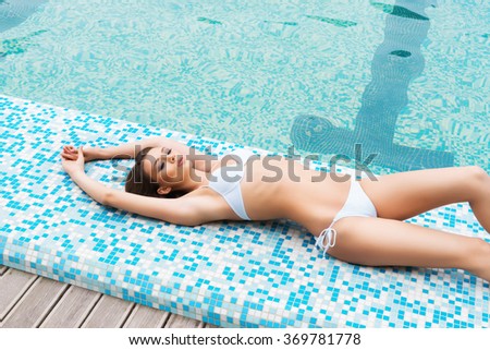 Young and sporty woman in swimsuit. Girl relaxing in a pool at summer.