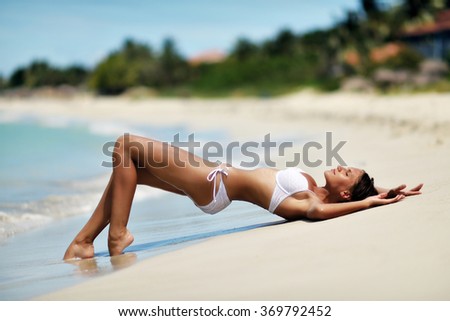 girl in a white bathing suit lying on the sand