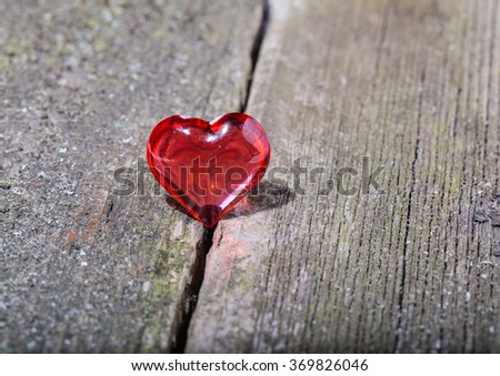 Red transparent glass heart on old gray boards. Close up
