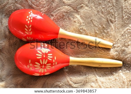 Couple of bright red wooden maracas on brown background in sunny day