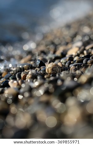 Photo blurred closeup large quantities of wet grey smooth fragments clasts of marine rubbles pebbles stones rocks of various sizes forms surface outdoor on shingle beach background, vertical picture 