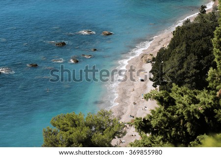 Photo of beautiful seaside seen from above shingle beach line blue sea and rich green foliage trees water-based leisure area on coastlines background, horizontal picture