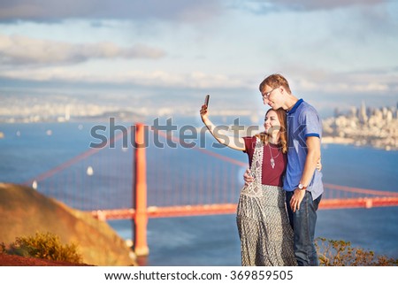 Romantic loving couple making selfie in San Francisco, California, USA. Golden gate bridge in the background