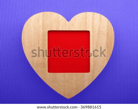 Wooden picture frame with love heart on crepe paper background.