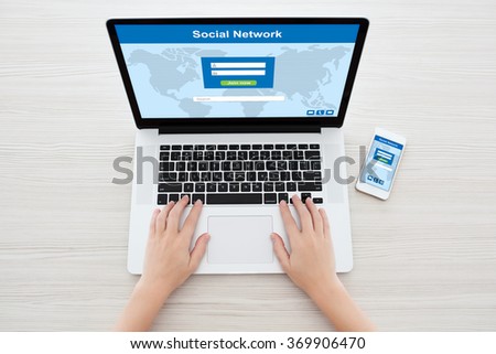 Female hands typing on a notebook keyboard with social network on the screen and phone in the office