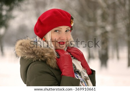 Mature woman in red beret and winter clothes on blur natural snowy background - with warming photo filter