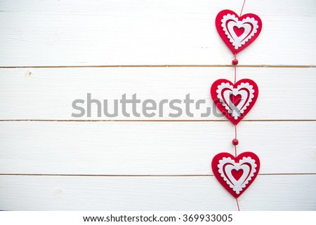 Frame of hearts hanging on white painted rustic wooden background