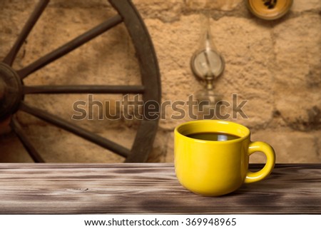 Coffee in cup on wooden table opposite defocused vintage background.