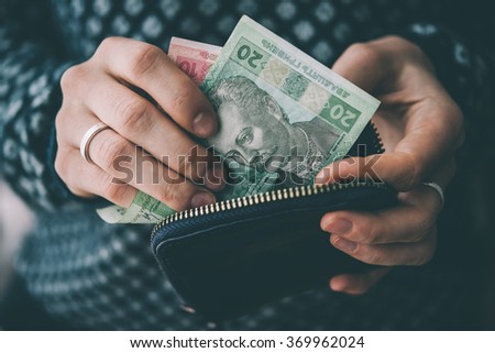 Hands holding ukrainian hryvnia bills and small money pouch. Toned picture