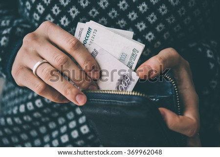 Hands holding russian rouble bills and small money pouch. Toned picture
