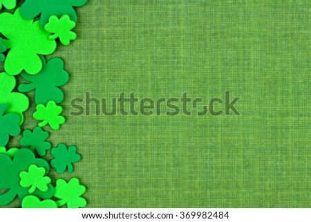 St Patricks Day side border of shamrock confetti over a green linen background