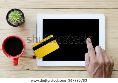 Asian man using credit card and digital tablet computer for buying on line. Online shopping concept.Beautiful hand holding credit card.Man using tablet computer on desk table.Flat lay images.