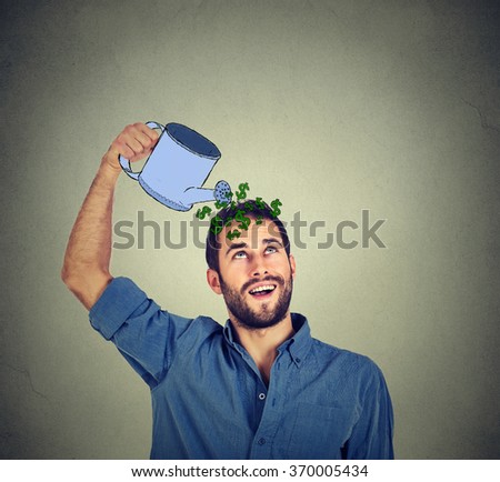 happy young man watering himself with money