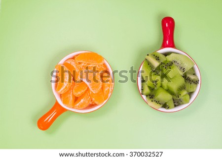 Slices of tangerine and kiwi slices in the toes on a green background