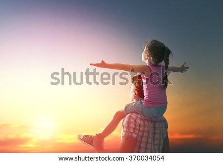 happy family at sunset. father and daughter having fun and playing in nature. the child sits on the shoulders of his father.