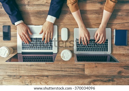 man and woman working on their computers. the view from the top. two laptops, two persons. Royalty-Free Stock Photo #370034096