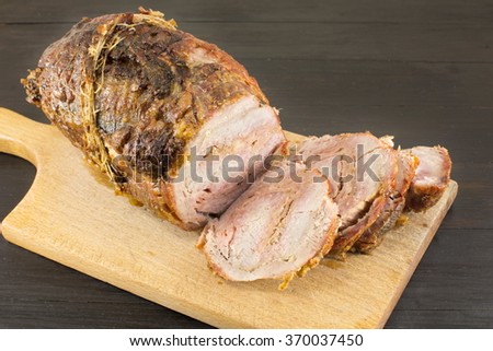 roasted rolled pork on a cutting board on a black table