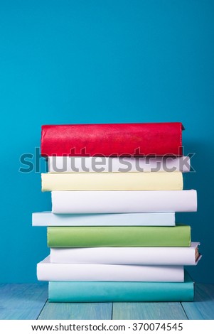 Stack of colorful books, grungy blue background, free copy space. Vintage old hardback books on wooden shelf, deck table, no labels, blank spine. Back to school,  instagram filter. 