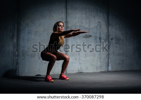 Attractive young woman doing sit ups exercise against concrete wall Royalty-Free Stock Photo #370087298