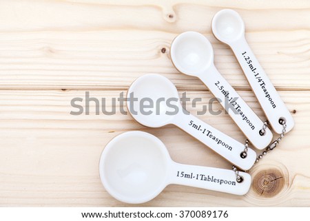 Ceramic measurement spoons on a pinewood background linked together and viewed from above. 