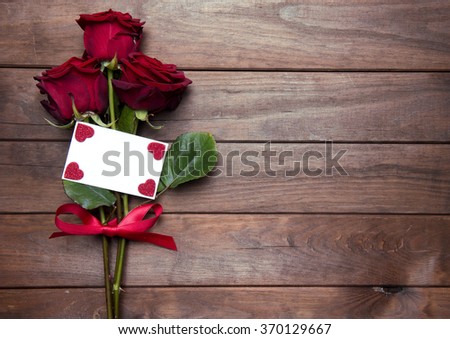 beautiful red roses with ribbon on wooden background