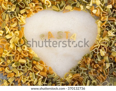 Multi Colored Pasta letters spelling Pasta on a marble slab, with an edging of pasta in a heart shape