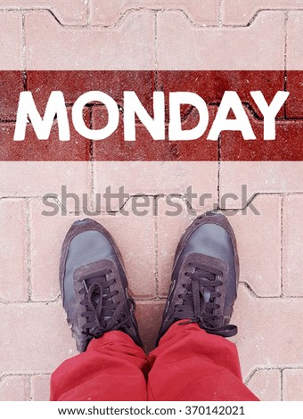 male legs in sneakers on the tiled road with sign monday