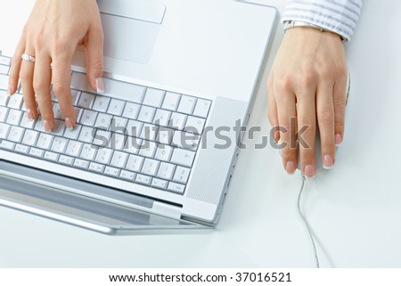 Closeup picture of female hand typing on computer keyboard, using mouse.