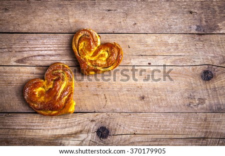 Homemade pastries. Bun heart on wooden background. Food