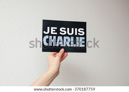 Je Suis Charlie in French language (translation I Am Charlie) card on woman's hand on gray background