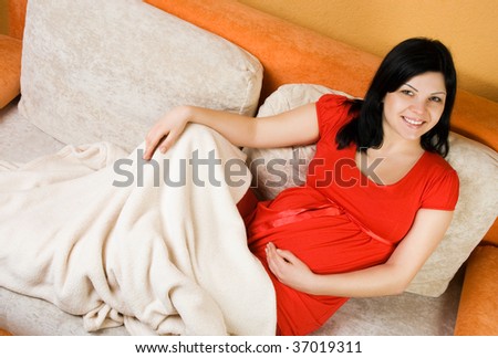 Beautiful pregnant woman sitting on the couch