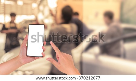 image of hand holding smartphone and blur technician fixing car in the garage.