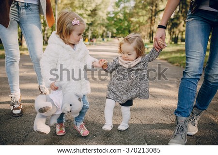 great trendy young mothers walking in the park with his daughters in beautiful clothing
