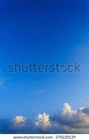 fluffy clouds above clear blue sky background