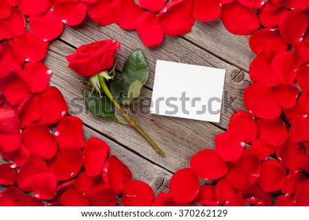 Valentines day greeting card over wooden background and red rose petals
