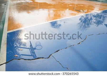 Reflection in a puddle of a basketball hoop.