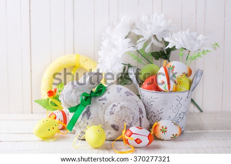 Colorful easter eggs and decorative  rabbit  on white  wooden background. Easter background. Selective focus is on eggs.  
