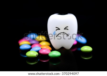 Tooth decay is crying with emotions sugar coated chocolate on the side. On a black background