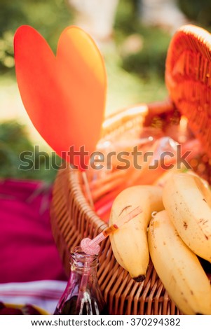 Picnic basket with fruits on grass on bright background
