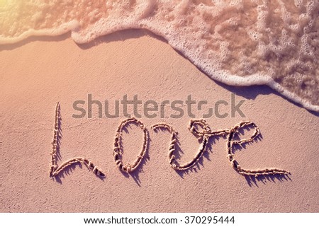 the word love on a tropical beach with wave on background
