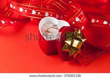 close-up image of wedding rings in a gift box on red background