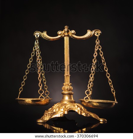Symbol of justice, golden law scales on dark studio background