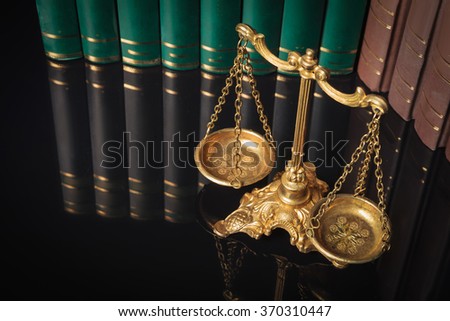 above picture of a golden justice scales in front of law books 