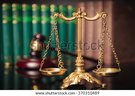 golden scale in front of judge's gavel and law books, justice concept
