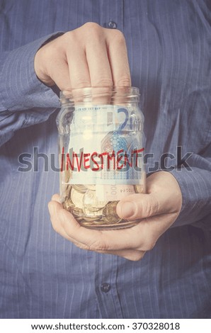 Hands with money in glass jar, close up. Saving Concept.