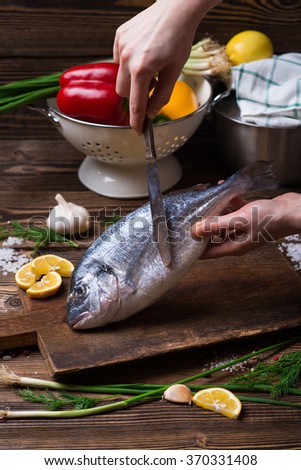 Delicious fresh sea fish on dark wooden background. Healthy food, diet or cooking concept

