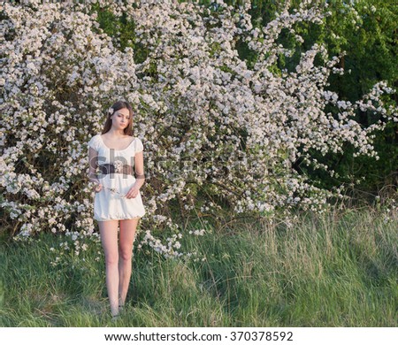 Beautiful young girl on background flowering apple-tree