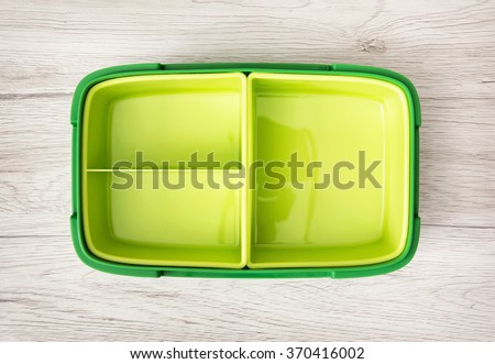Green plastic box for food storage on the wooden background. Royalty-Free Stock Photo #370416002