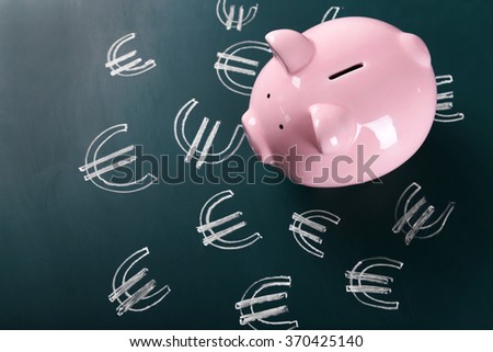 Piggy bank on chalkboard with Euro currency symbols