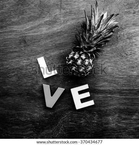 word love made up of colorful wooden letters with little pineapple instead of letter O on a wooden board. February 14, Valentine's Day